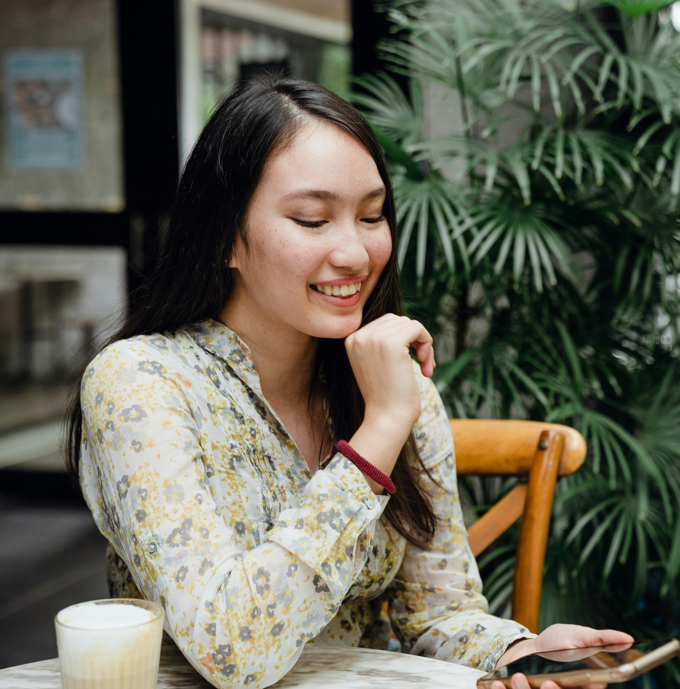 Woman drinking coffee and rating business on her phone.