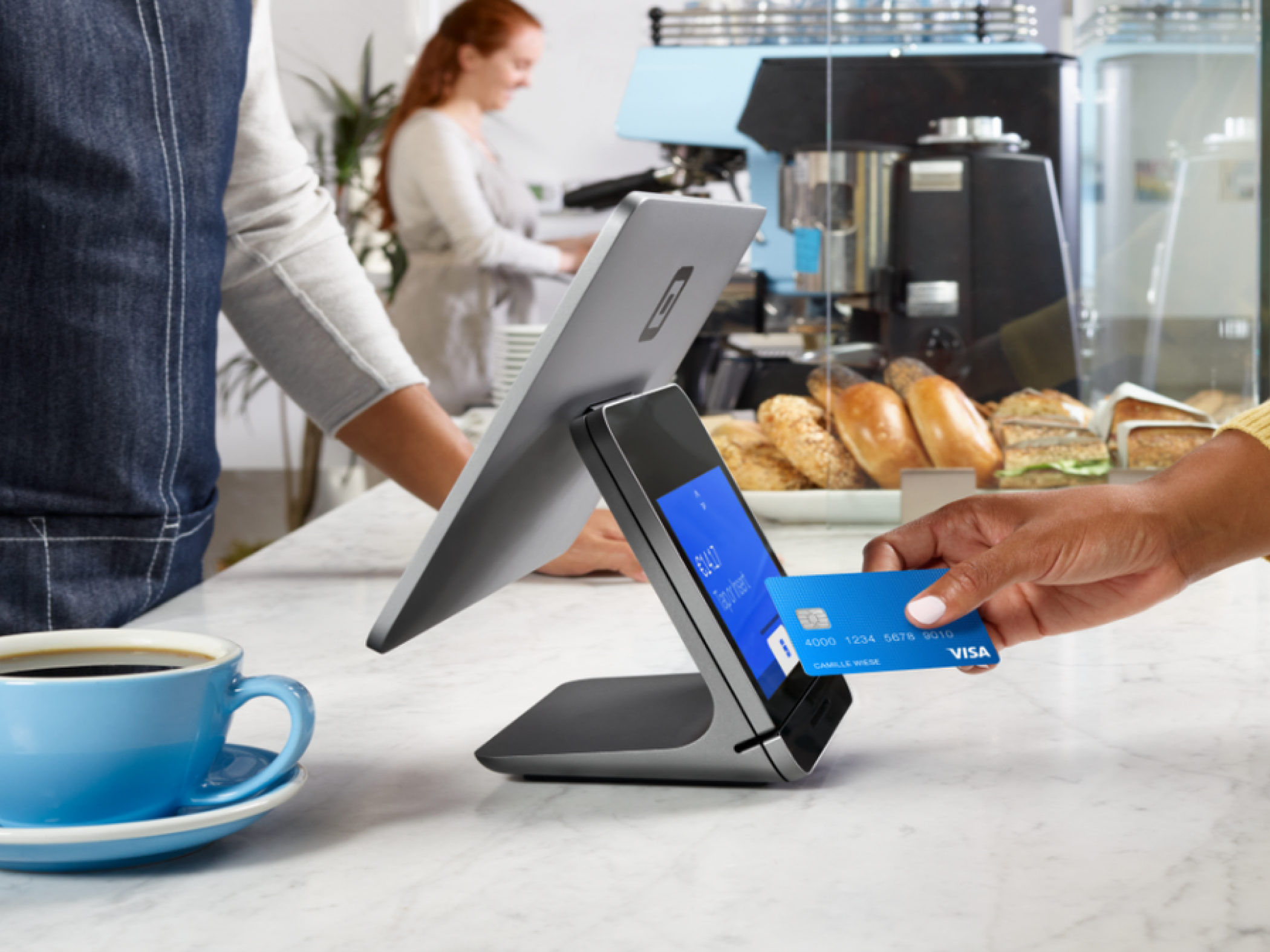 Hand tapping credit card on Square register in cafe.