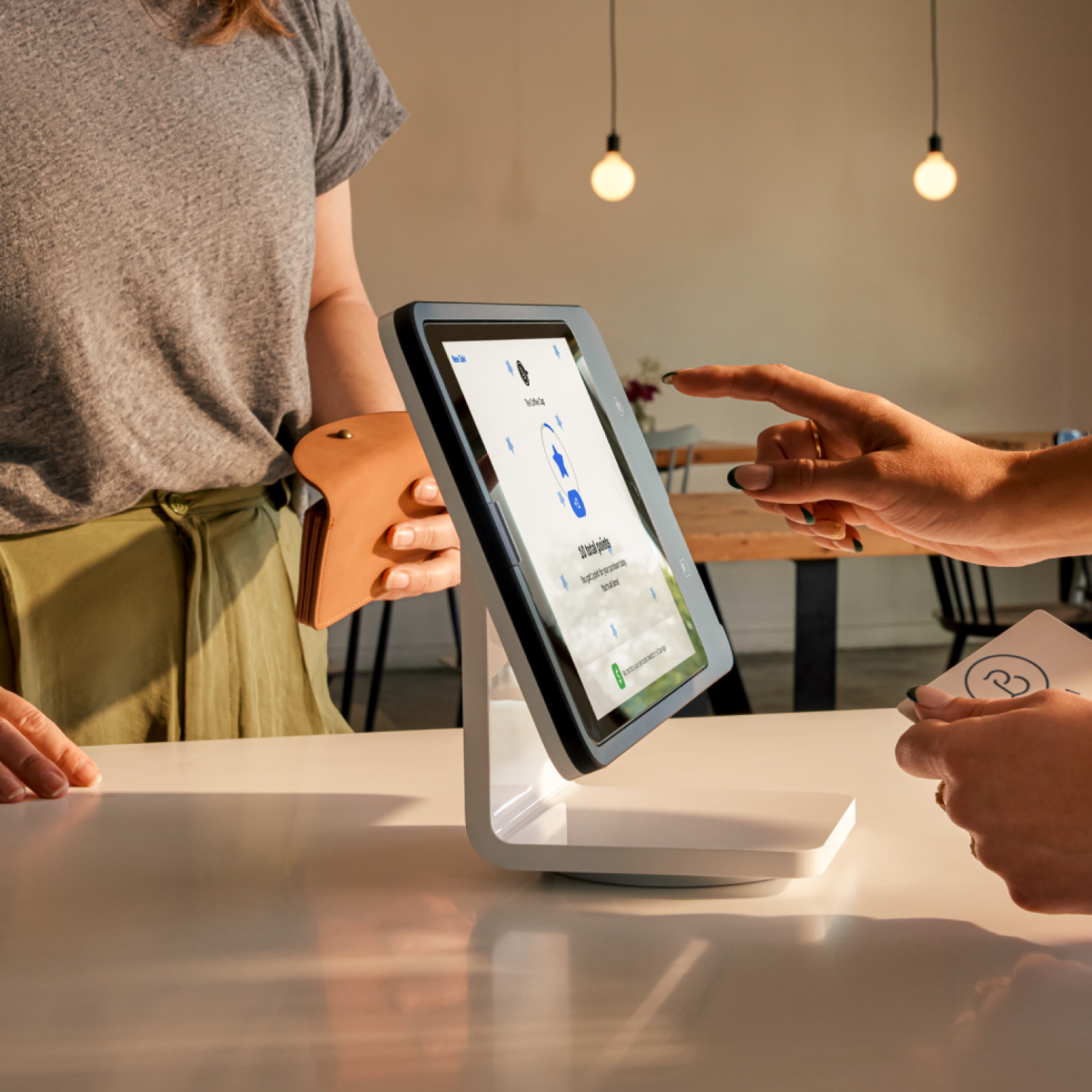 Restaurant female cashier checking out female guest at Square stand POS.