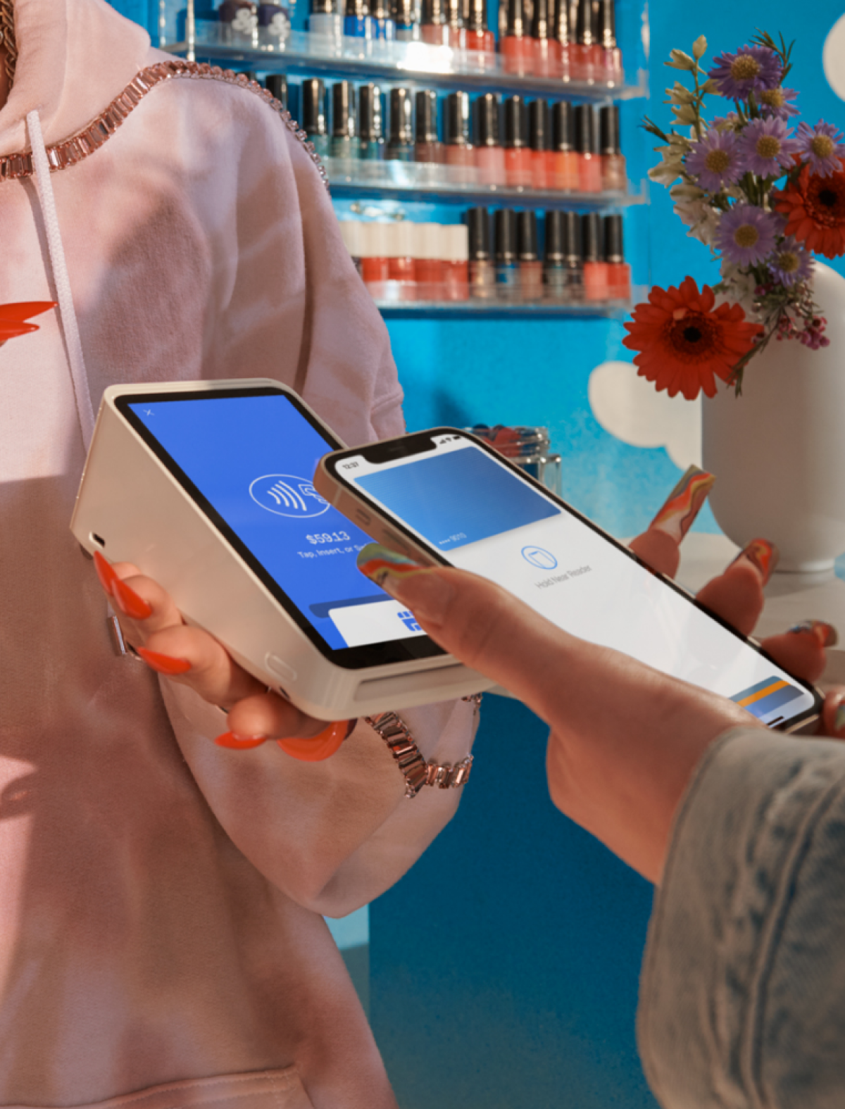 Female employee accepting payment on Square terminal in nail shop.